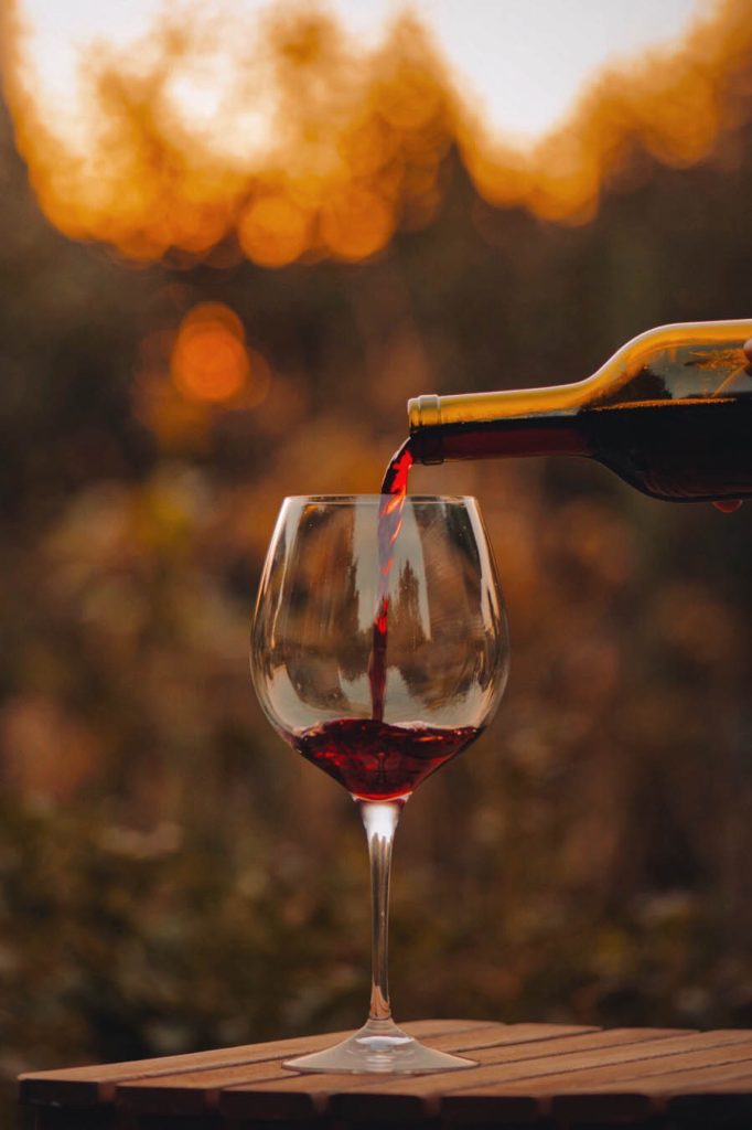 Red wine poured into a glass at sunset